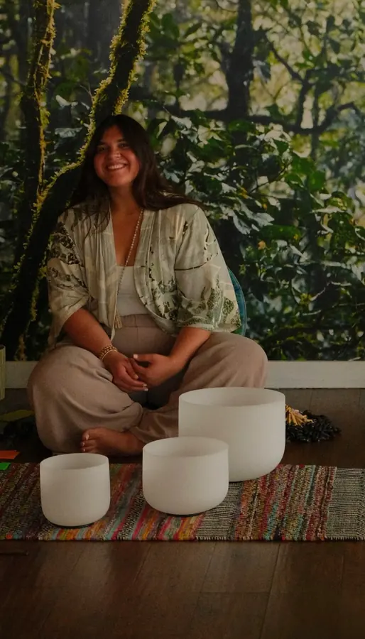 Adela King, co-founder of Half Pigeon Yoga, seated with crystal singing bowls in the studio
